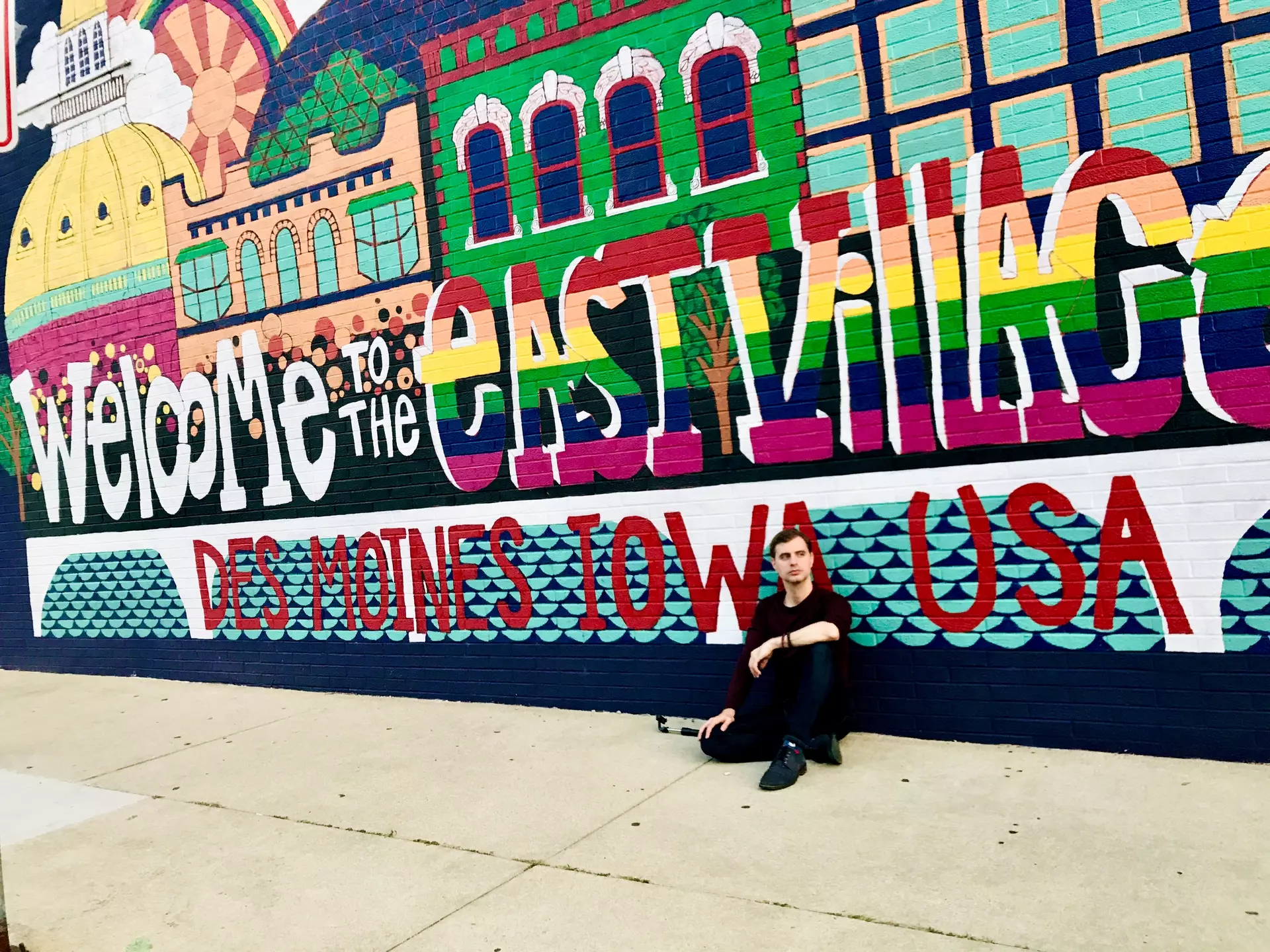 Michael sitting in front of a mural in East Village, a neighborhood in Des Moines, Iowa.
