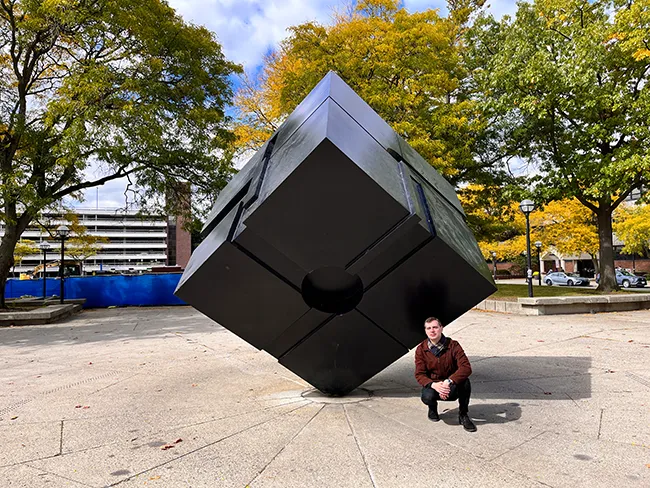 Author kneeling beside The Cube.