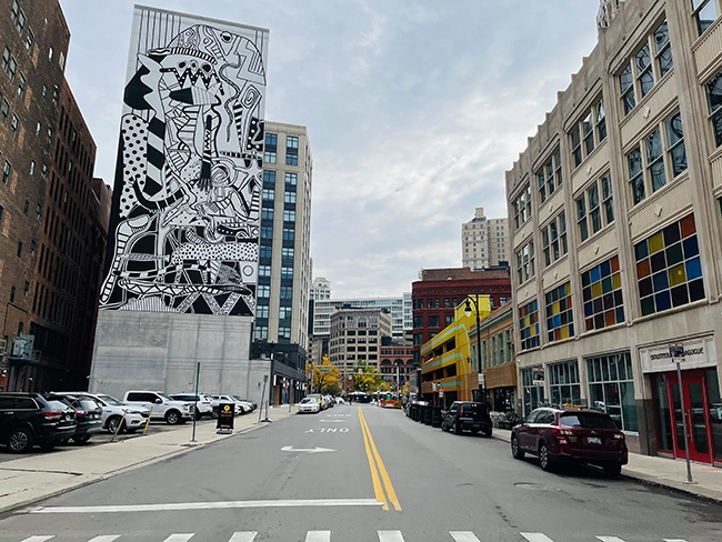 A black & white mural on a building with a painted parking structure on the side in Detroit.